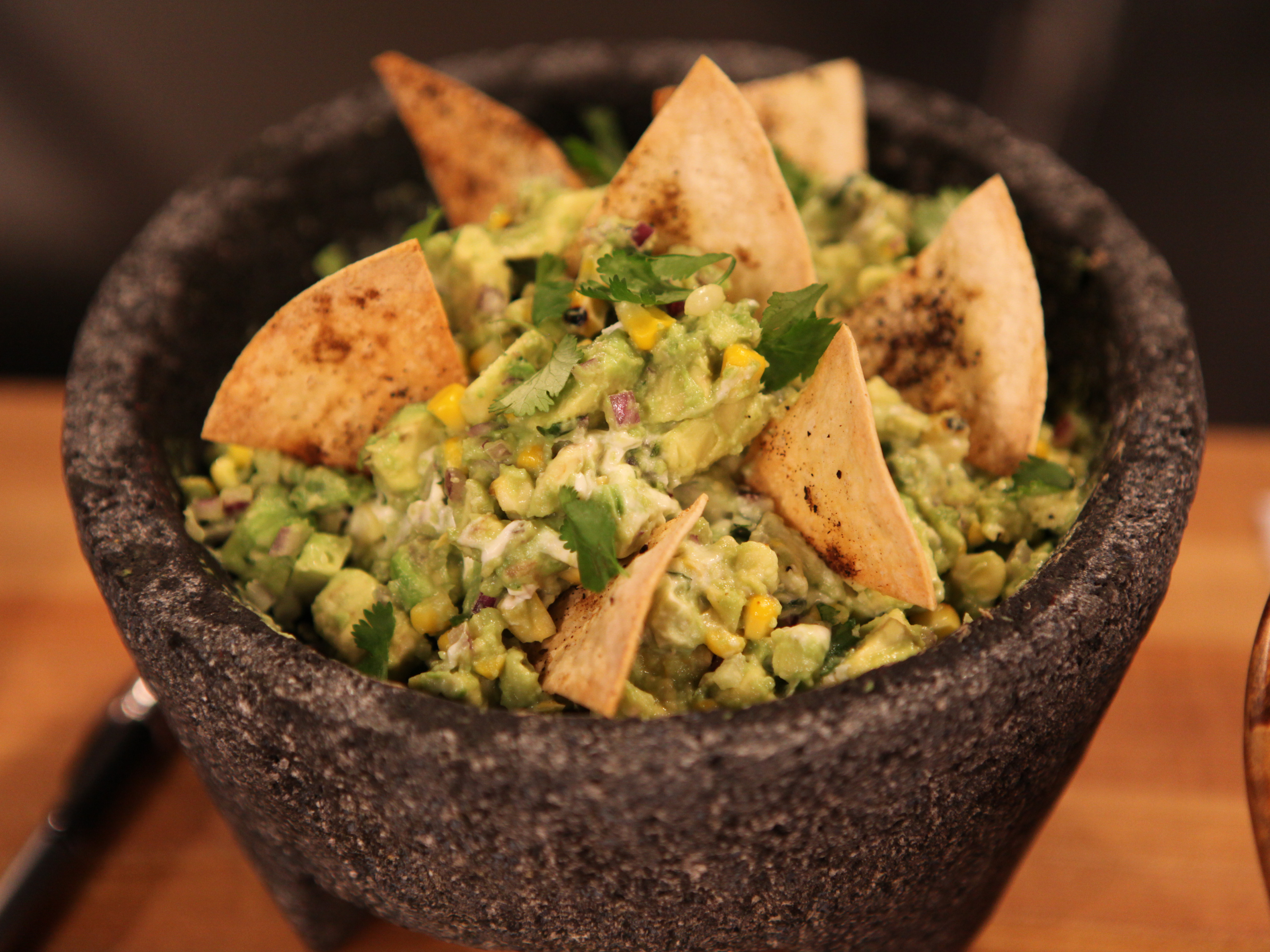 Bowl of guacamole on Mexican comal decorated with tortilla chips